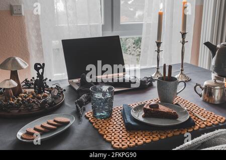 Table with laptop, cake, cookies and autumnal decoration in a cozy room prepared for virtual coffee with family or friends, useful during worldwide co Stock Photo