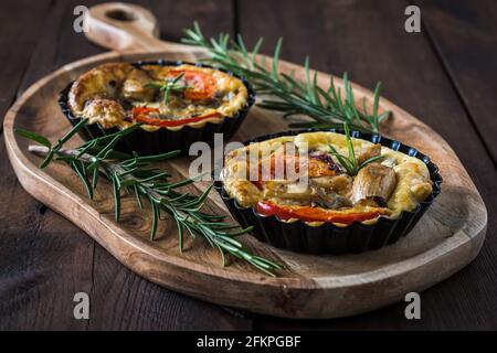 Two vegetarian tartlets on wooden board on a rustic dark wooden table Stock Photo