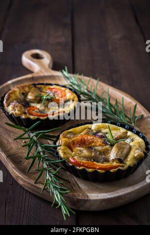 Two vegetarian tartlets on wooden board on a rustic wooden table, vertical stock photo with copy space Stock Photo