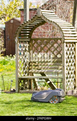 Husqvarna robotic robot  automatic lawn mower in use in an English country garden mowing and cutting  a grass lawn Stock Photo