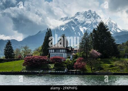 Landscape view of a beautiful house on the shores of the lake of Luzern, with snowy mountains in the background, shot in Luzern, Switzerland Stock Photo