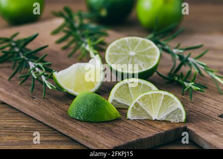Sliced limes and rosemary branches on a wooden board Stock Photo