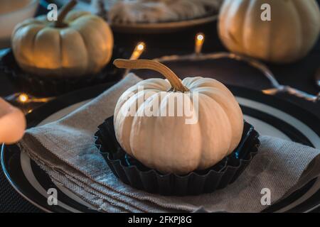 Place setting with a white mini pumpkin on a black and white decorated eating table Stock Photo