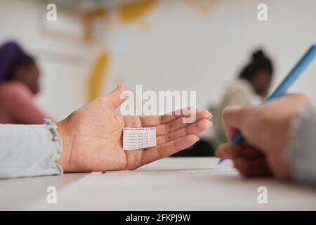 Close up of unrecognizable female student hiding cheat note while taking exam in school, copy space Stock Photo
