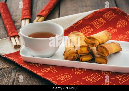Mini spring rolls with sweet spicy dip on a white plate on a red chinese place mat Stock Photo