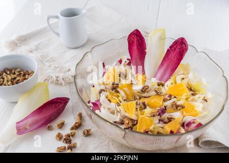 Chicory salad with orange and walnuts on white background Stock Photo