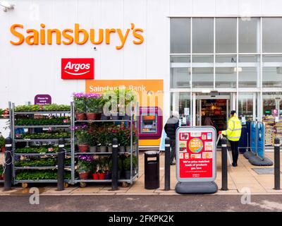 Customers queueing at Sainsburys supermarket during the Coronavirus lockdown where social distancing is required and numbers in the shop are limited Stock Photo