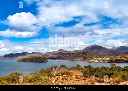 SHIELDAIG WESTER ROSS HIGHLANDS SCOTLAND SPRINGTIME VIEW OVER LOCH SHIELDAIG TO THE VILLAGE HOUSES THE ISLAND WITH TREES AND MOUNTAINS BEYOND Stock Photo