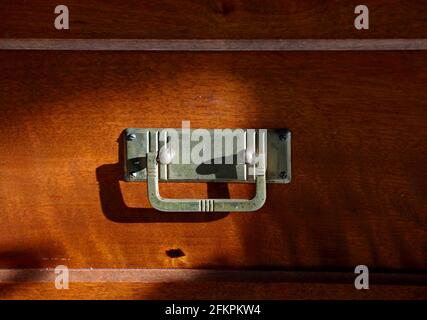 A closeup of a brass pull of a wooden drawer Stock Photo