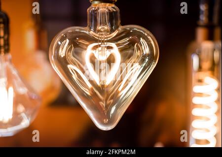 Many differently shaped incandescent bulbs are suspended in the dark Stock Photo