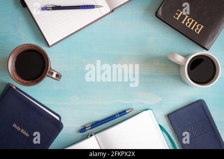 frame of two coffee cups, bibles and journals with pens and a prayer book with copy space on blue wood background in table top view Stock Photo