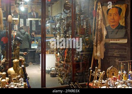 Pingyao in Shanxi Province, China: A store in Pingyao at night selling antiques and communist memorabilia. Picture of Chairman Mao Zedong. Stock Photo