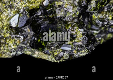 Closeup of Epidote crystal cluster. Larger black and green specimen, surrounded by smaller crystals. From Pakistan. Stock Photo