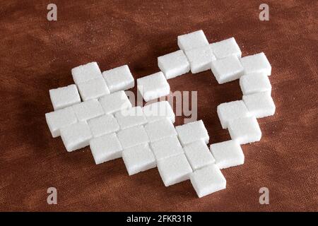 Sweet cute heart made of sugar cubes on brown natural background texture, love,sweets,candy,sugar,food concept modern design Stock Photo