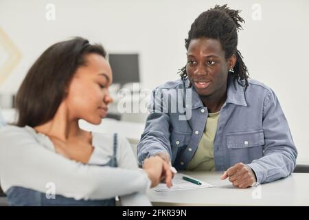 Portrait of two African-American students passing notes during class in school, copy space Stock Photo