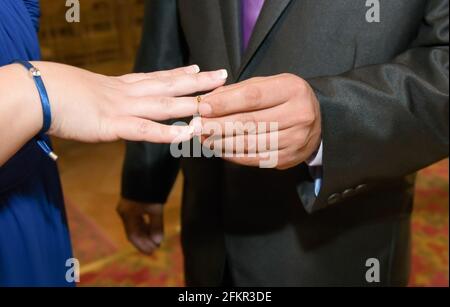 Gold ring placed by the groom on the bride's finger on her wedding day. Stock Photo