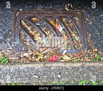 Blocked drain grating in roadside gutter Stock Photo