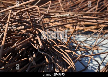 Curved rusty metal rods closeup. Pile of uneven metal bars covered with brown rust. Stack of iron sticks. Old iron construction armature closeup. Cons Stock Photo