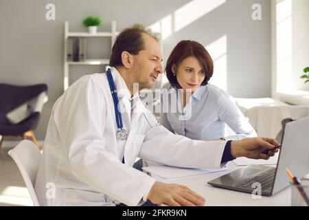 Woman listening to doctor and looking at laptop screen with health screening results Stock Photo