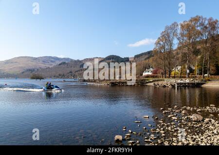 Two people on a jet ski heading to a pier on Loch Earn at St Fillans, Scotland Stock Photo