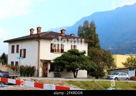 Building set in a small town in Switzerland with mountains in the background, tree and car parked Stock Photo