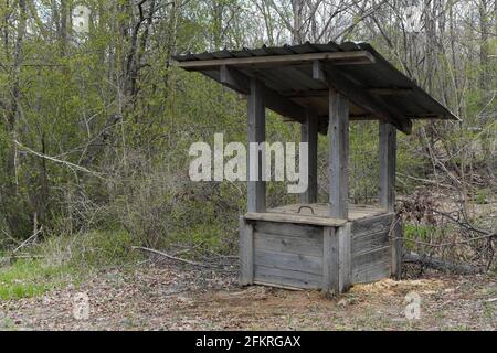 An old wooden well in the spring forest on the bank of a stream. Selective focus. Stock Photo