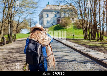 Tourist woman visiting Olesko Castle walking along alley to ancient landmark. Travelling in Western Ukraine. Stock Photo