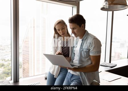 Successful young employees cooperate on laptop in office Stock Photo