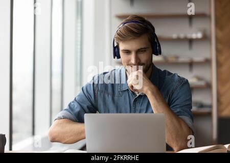 Smiling male in earphones study online on laptop Stock Photo