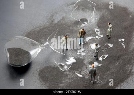 miniature people. figures people stand near the broken hourglass. business crisis. stop time process Stock Photo