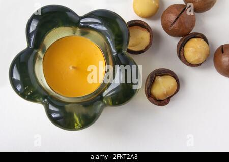 Decorative glass candlestick and macadamia nuts on white background. Stock Photo