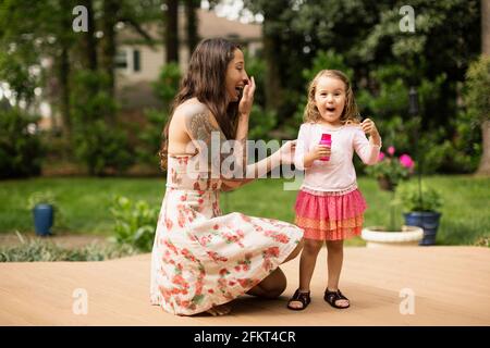 Mother and toddler daughter blowing bubbles in garden Stock Photo