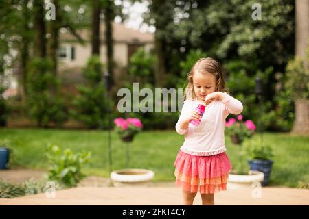 Female toddler preparing to blow bubbles in garden Stock Photo