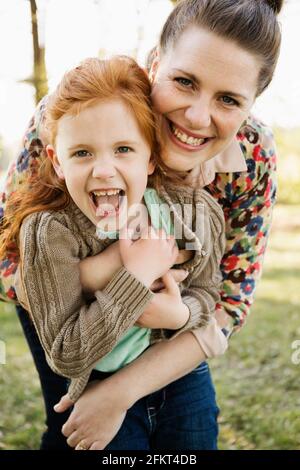 Portrait of mid adult mother hugging daughter in park Stock Photo