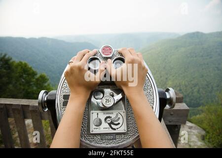 Mid adult woman holding coin operated binoculars,  focus on hands, New River Gorge National River, Fayetteville, West Virginia, USA Stock Photo