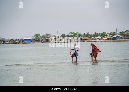 Khulna, Bangladesh. 25th Apr, 2021. A man with his wife returning home after doing daily shopping in a village next to the Sundarbans forest in Khulna. Credit: SOPA Images Limited/Alamy Live News Stock Photo