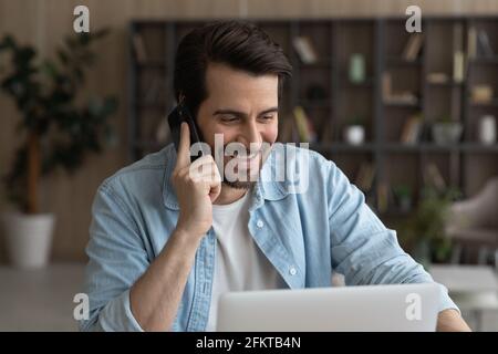 Close up smiling businessman talking on phone and using laptop Stock Photo