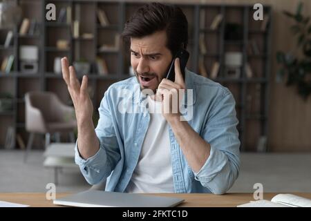 Angry irritated man talking on phone, arguing or complaining Stock Photo