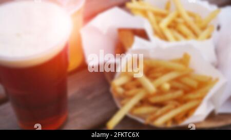 Blurred abstract background. Dark beer and fries on a wooden table. Food court. Takeaway food, food festival. Unhealthy food concept Stock Photo