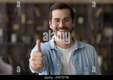 Head shot portrait smiling man in glasses showing thumb up Stock Photo