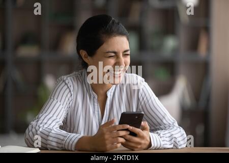 Close up excited Indian woman laughing, holding smartphone, having fun Stock Photo