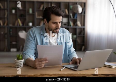 Focused businessman using laptop, working with financial documents, research project Stock Photo