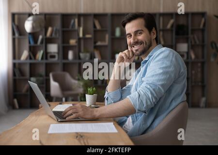 Portrait smiling successful businessman sitting at desk with laptop Stock Photo
