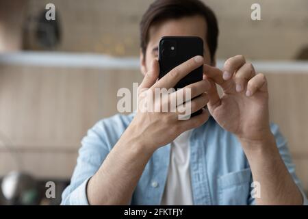 Close up cropped of young man using smartphone, browsing apps Stock Photo