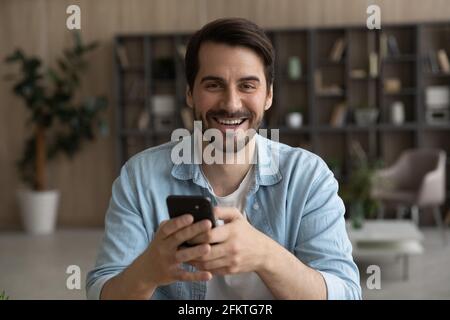 Head shot portrait laughing man holding smartphone, having fun Stock Photo