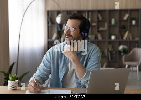 Dreamy man in headphones and glasses distracted from online studying Stock Photo