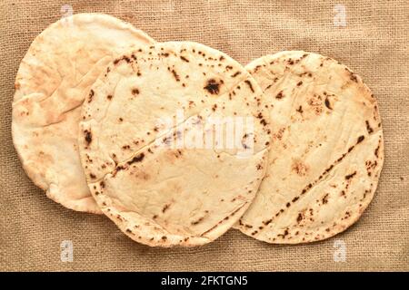 Several freshly baked pita bread on burlap, close-up, top view. Stock Photo