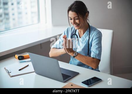 Cheerful female doctor using modern laptop at work Stock Photo