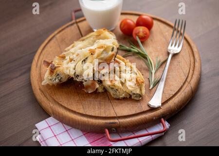 Traditional balkan breakfast - Burek pie with cheese and spinach served on vooden table.