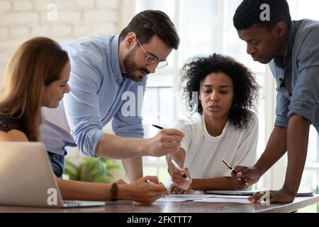 Concentrated young mixed race colleagues discussing research report results. Stock Photo